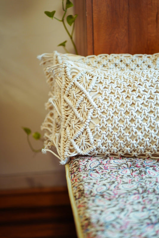 Handwoven macramé cushion cover with intricate knotted detailing and a soft bohemian texture.