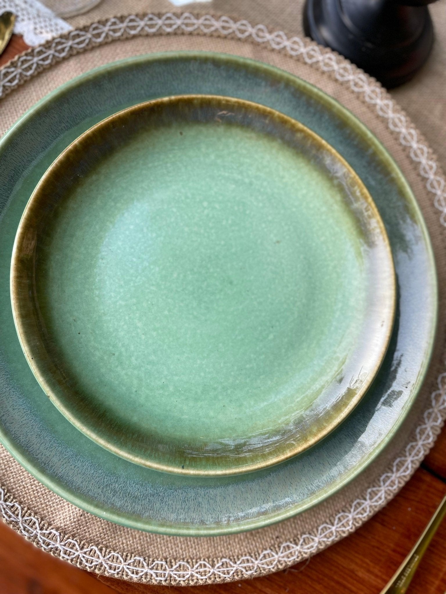 Green ceramic plate on a textured surface with a lace doily