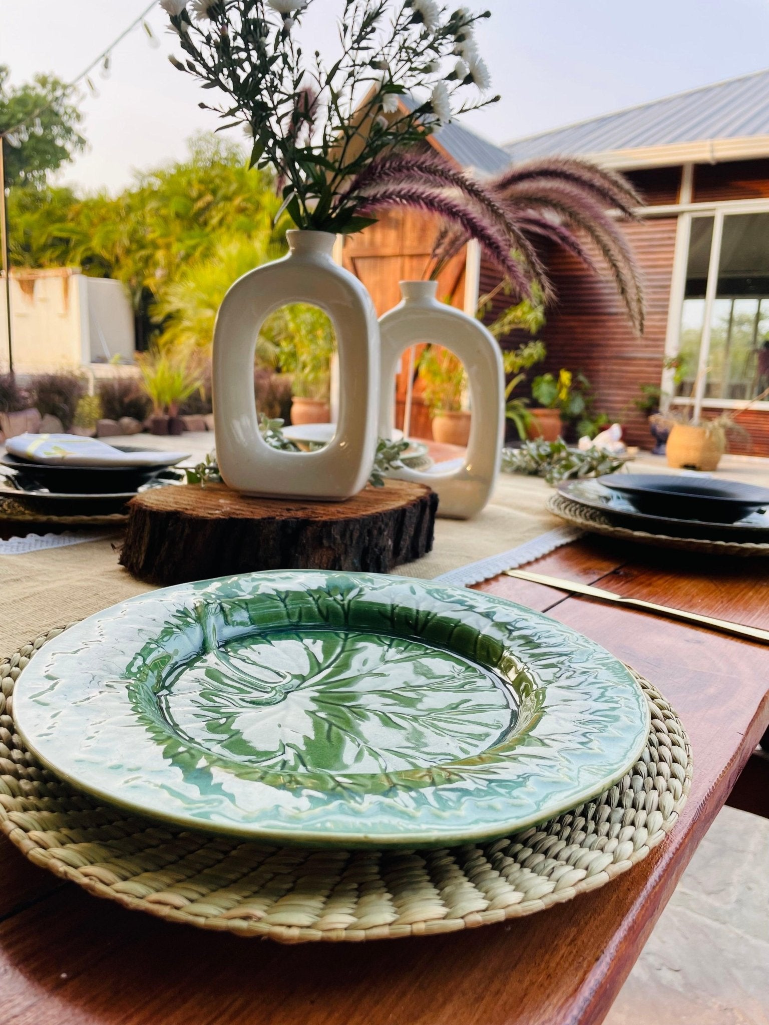 Decorative ceramic plate on a woven placemat with a garden setting in the background