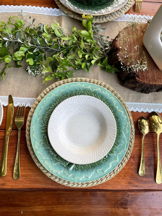 Table setting with green plates, gold cutlery, and a wooden log in the background.