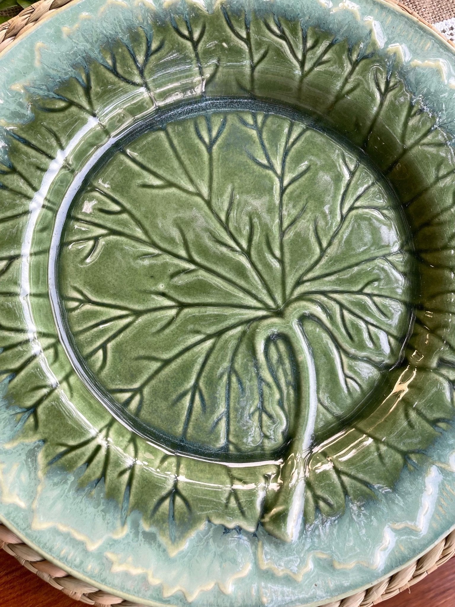 Green ceramic plate with leaf pattern on a woven surface