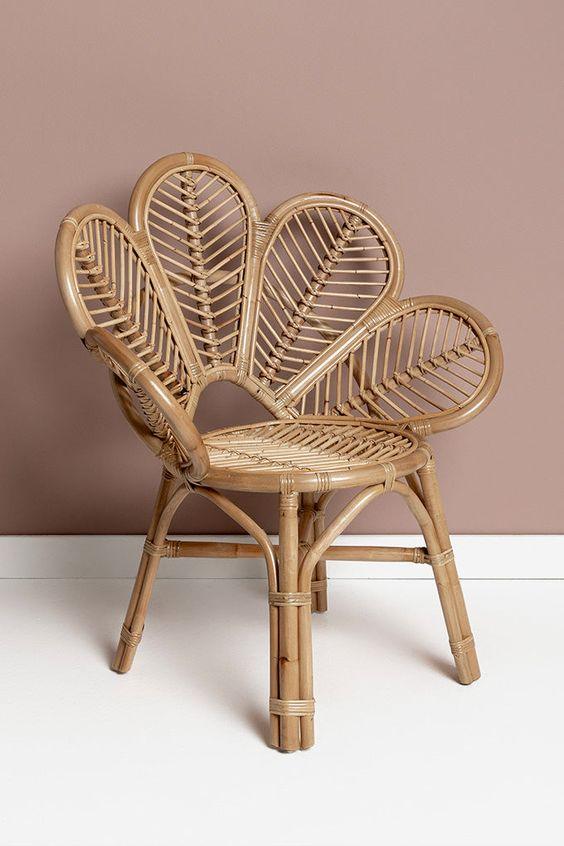 Woven rattan chair with a leaf-like design against a beige wall.