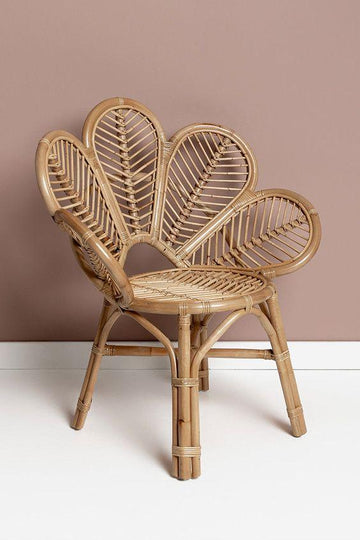 Woven rattan chair with a leaf-like design against a beige wall.
